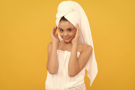 cheerful teen kid in shower towel with cream on faceの写真素材