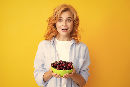 Young stylish woman isolated holding red colorful cherries. Berries harvest season. Summer diet with organic harvesting cherry.の写真素材