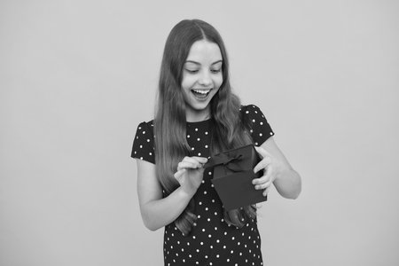 Cute teenager child girl congratulate with valentines day, giving romantic gift box. Present, greeting and gifting concept. Birthday holiday concept. Excited face of teenager girl.の写真素材