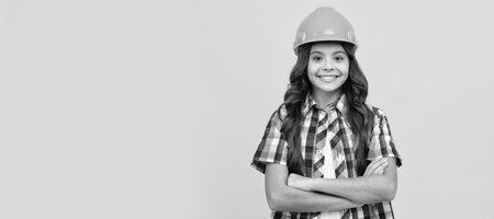 Engineer teenager girl. happy child with curly hair in construction helmet, contractor. Child builder in helmet horizontal poster design. Banner header, copy space.の写真素材