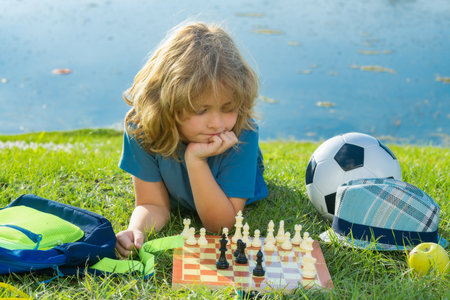 Chess game for kids. Child playing chess outdoor in park.の写真素材