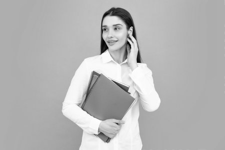 Smiling young woman college student holding book on isolated gray background. Model emotionally showing facial expressions.の写真素材