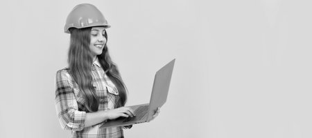 check the email. happy labour day. future career. teen girl in helmet use laptop. Child builder in helmet horizontal poster design. Banner header, copy space.の写真素材