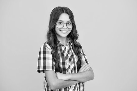 Teenager girl crossed arms isolated on yellow background. Studio portrait of child with mock up copy space.の写真素材