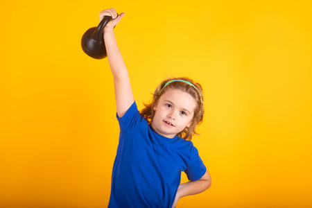 Sporty kids, studio isolated portrait on yellow background. Kids sports exercises. Healthy kids life and sport concept. Portrait of child boy working out with dumbbells.の写真素材