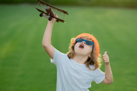Children day. Kid pilot aviator with with paper wings dreams of traveling in summer in park outdoor.の写真素材