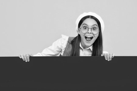 Surprised teenager girl holds a blank for notification informing. Advertisement and sale. Markets and shops sales concept, blank board for copy space.の写真素材