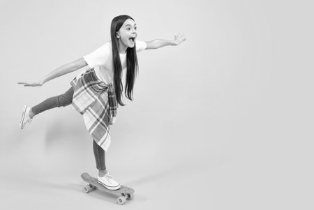 Studio shot of trendy teenage fashion model in casual look. Teenager youth hipster urban lifestyle. Child girl in street style with a skateboard. Happy teenager, smiling emotions of teen girl.の写真素材