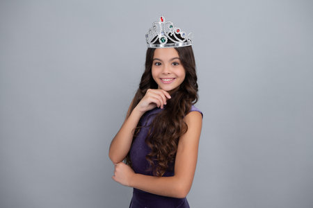 Little queen wearing golden crown. Teenage girl princess holding crown tiara. Prom party, childhood concept. Happy girl face, positive and smiling emotions.の写真素材