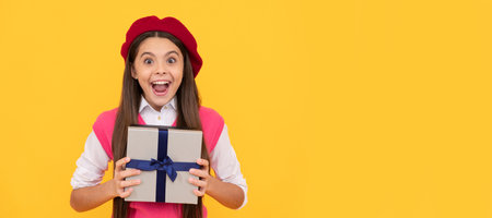 surprised teen girl in french beret hold present or gift box on yellow background, surprise. Kid girl with gift, horizontal poster. Banner header with copy space.の写真素材