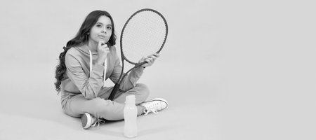 thinking child with tennis racquet. teen girl after sport training. dedicated to fitness. Horizontal poster of isolated child face, banner header, copy space.の写真素材