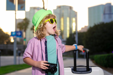 Child tourist with luggage travel bag travelling. Kid with suitcase walk on city street outdoor....