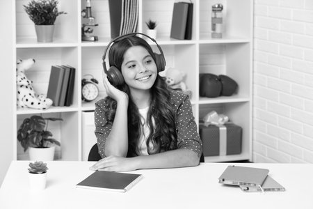 Teenager school girl listening music. Portrait of teen with headphone. Children, music, emotions concept. Excited schoolgirl. Happy girl face, positive and smiling emotions.の写真素材