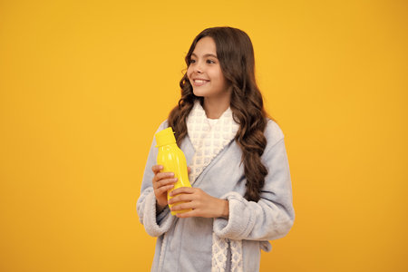 Teen girl with water from plastic bottle on isolated background, copy space. Kid girl care body hydration. Active leisure and water balance.の写真素材