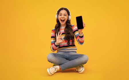 Portrait of cute teenage girl using mobile phone, chatting on web, typing sms message. Mobile app for smartphone. Children lifestyle concept. Mock up copy space.の写真素材