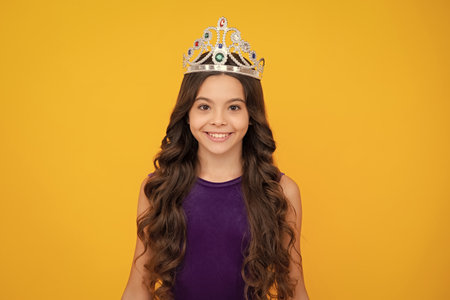 Girls birthday party, funny kid in crown. Imagine herself a queen, child wear diadem. Successful teenager wear luxury beauty queen crown, success. Happy girl face, positive and smiling emotions.の写真素材