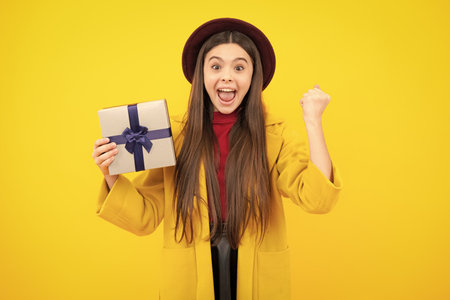 Emotional teenager child hold gift on birthday. Funny kid girl holding gift boxes celebrating happy New Year or Christmas. Excited teenager, glad amazed and overjoyed emotions.の写真素材