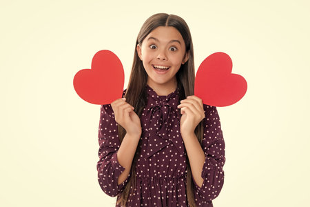 Happiness kids and love concept. Romantic lovely teen girl with red heart, world heart day, happy valentines day. Portrait of emotional amazed excited teen girl.の写真素材