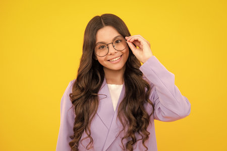 Teenager child wearing glasses on yellow studio background. Cute girl in eyeglasses.の写真素材