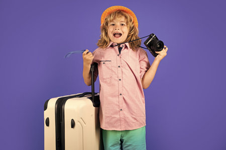 Child travel with travel bag. Child with suitcase dreams of travel, adventure, vacation. Studio kids portrait.の写真素材