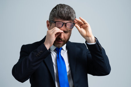 Tired man suffering from headache, exhausted with closed eyes touching head, relieving pain, migraine. Business problems. Bankruptcy, financial problem and crisis concept.の写真素材