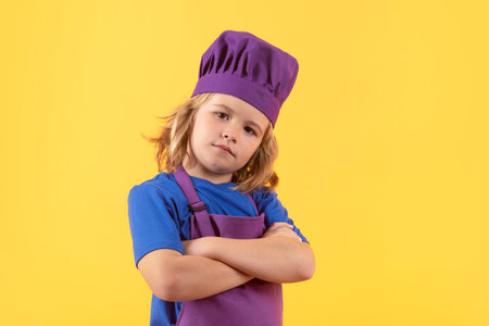 Kid chef cook prepares food on isolated studio background. Kids cooking. Teen boy with apron and chef hat preparing a healthy meal.の写真素材