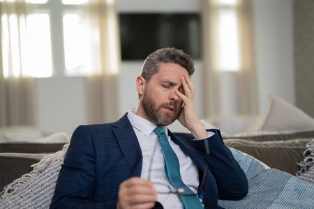 Tired, headache and eye strain from laptop. Businessman with stress, burnout and fatigue eyestrain. Business man rubbing tired eyes after computer work.の写真素材