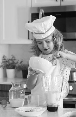 Kid chef cook cookery. Cooking children. Child boy with apron and chef hat preparing a healthy meal in the kitchen. Cooking process.の写真素材