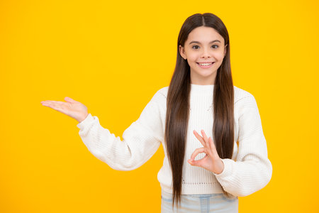 Teenager child pointing to the side with a finger to present a product or idea. Teen girl in casual outfit pointing empty space.の写真素材