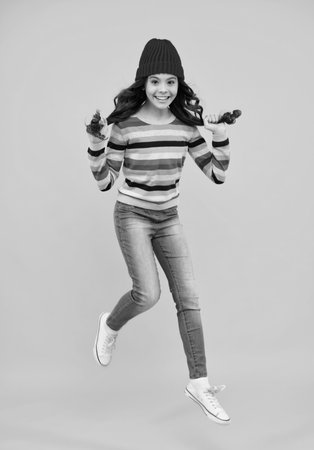 Fashion happy young woman in knitted hat and sweater having fun over colorful blue background. Jump and run. Happy teenager, positive and smiling emotions of teen girl.の写真素材