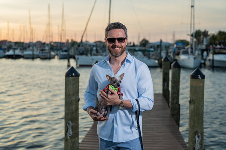 Rich summer business man near the yacht. Portrait of fashion male model outdoor. Rich male posing near yachts. Rich man in urban style. Rich man at yacht club. Man in gulf near luxury yacht ships.の写真素材