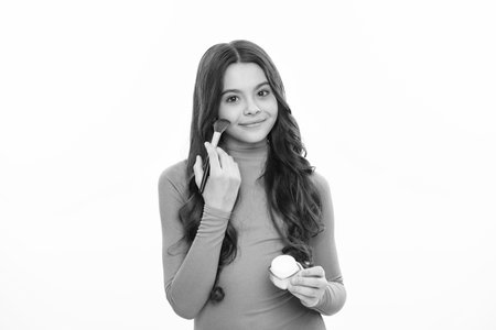 Child teen girl making beauty make up, hold powder and brush. Beautiful teenager applying makeup with powder. Happy girl face, positive and smiling emotions.の写真素材
