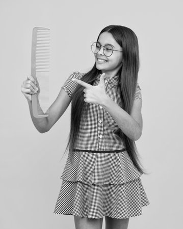 Teenager girl with long hair holding comb hairbrush for combing, beauty. Conditioner shampoo hair. Beauty kids salon. Child hairstyle.の写真素材