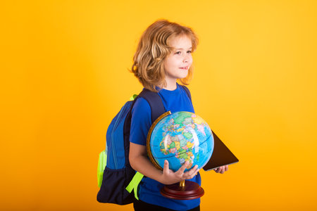 School boy world globe and tablet. School child studying in classroom at elementary school. Kid studying on lesson on yellow isolated background.の写真素材