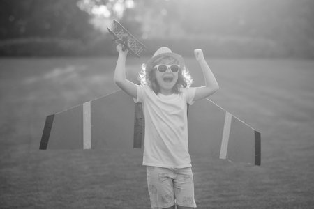 The concept of child kindness and childhood. Kid playing with toy airplane and dreaming future. Happy boy pilot play with airplane outdoors.の写真素材