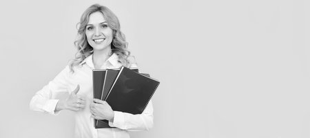 Business woman with book. happy blonde businesswoman woman in white shirt hold notepad or notebook, thumb up. Woman isolated face portrait, banner with mock up copy space.の写真素材