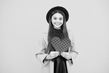 Lovely teenager portrait. Teenage girl hold shape heart, heart-shape sign. Child holding a red heart love holiday valentine symbol. Smiling girl.の写真素材