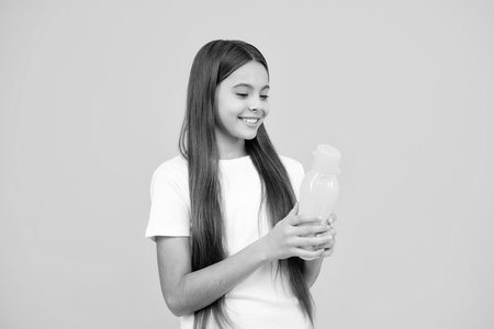 Child 12, 13, 14 years old with water bottle isolated studio background. Water bottle and healthy life. Health and water balance. Happy teenager portrait. Smiling girl.の写真素材