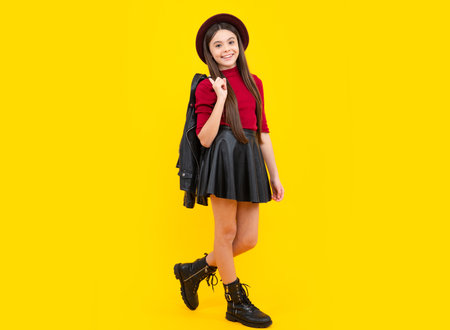 Full length photo of pretty teenager child girl wear casual leather skirt isolated on yellow background. Happy teenager portrait. Smiling girl.の写真素材
