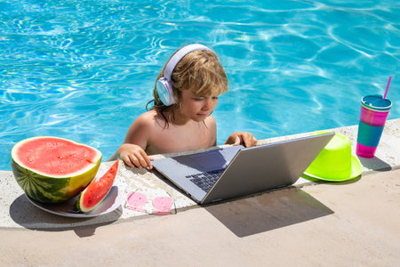 Child learning online computer laptop. Child relax and rest on colorful inflatable ring using computer in swimming pool. Summer business and technology. Summer travelling.の写真素材