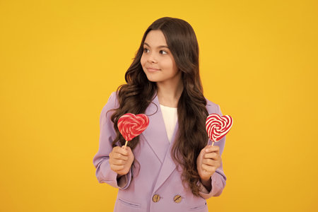 Hipster teenager child girl lick lollypop. Sugar nutrition, candy and sweets. Child eat lollipop  . Happy teenager, positive and smiling emotions of teen girl.の写真素材