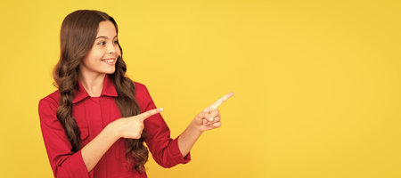 happy kid girl pointing finger on copy space for advertisement, promotion. Child face, horizontal poster, teenager girl isolated portrait, banner with copy space.の写真素材