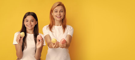 Mother and daughter kid banner, copy space, isolated background. happy family of woman and teen girl hold french macaron cookies, french macaroon.の写真素材