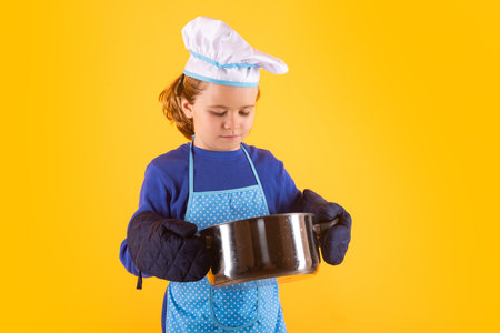 Kid cook with cooking pot. Chef child preparing healthy food. Studio portrait of child with chef hats.の写真素材