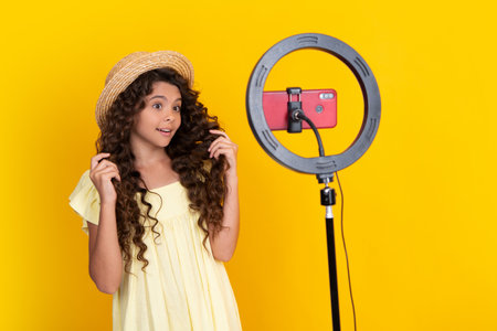 Teen girl speaking in front of camera for vlog isolated on yellow background. Teenager working as blogger, recording video blog. Happy teenager, positive and smiling emotions of teen girl.の写真素材