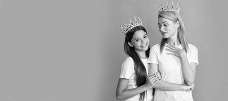 Mother and daughter child banner, copy space, isolated background. Selfish woman mother smile at happy girl child in crowns blue background, daughter.の写真素材