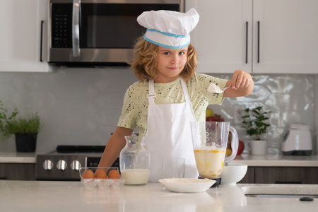 Kid chef cook cookery at kitchen. Cooking, culinary and kids. Little boy in chefs hat and apron.の写真素材