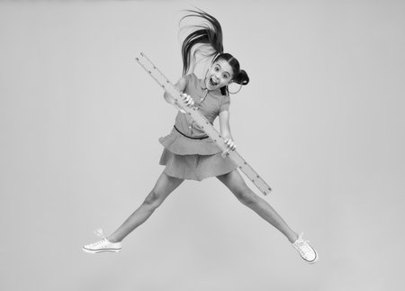 Amazed teenager. Back to school. School girl hold ruler measuring isolated on yellow background. Crazy jump, jumping kids. Excited teen schoolgirl.の写真素材