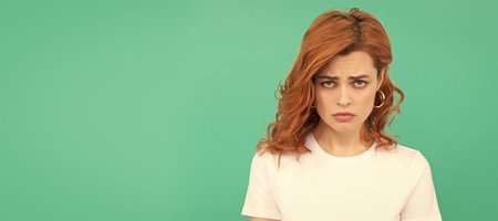 Woman isolated face portrait, banner with copy space. sad female fashion model. pretty look of young girl. portrait of redhead lady on blue background.の写真素材