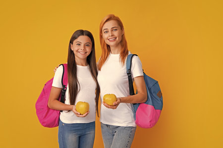 School, learning and education concept. Mother and daughter schoolgirls with school backpack and apple ready to learn. Back to school. Mother and daughter. Mom and childの写真素材